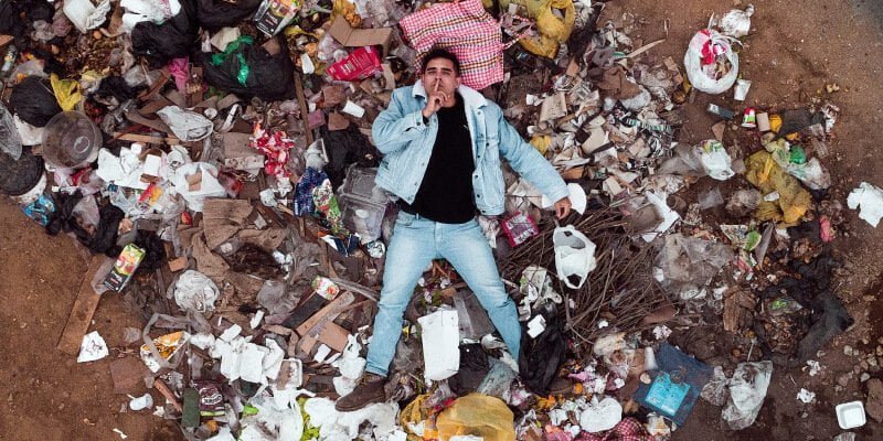 hombre rodeado de basura
