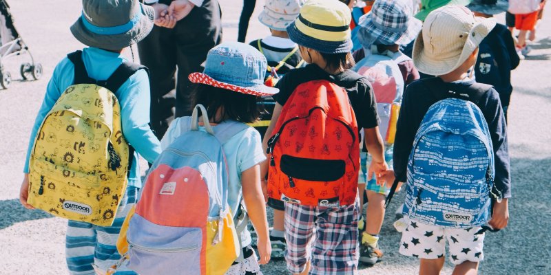 Niños con mochilas yendo al colegio